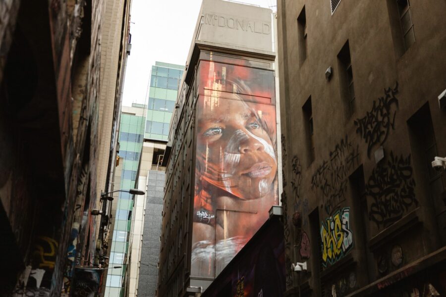 Inner city buildings, one with a mural of an Indigenous child painted on it