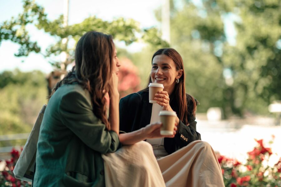 Two women chatting outdoors over take-away coffee