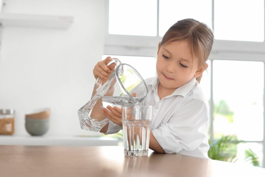 A young girl pouring herself a glass of water