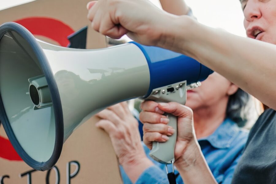 An outdoor protest; people holding signs and a megaphone