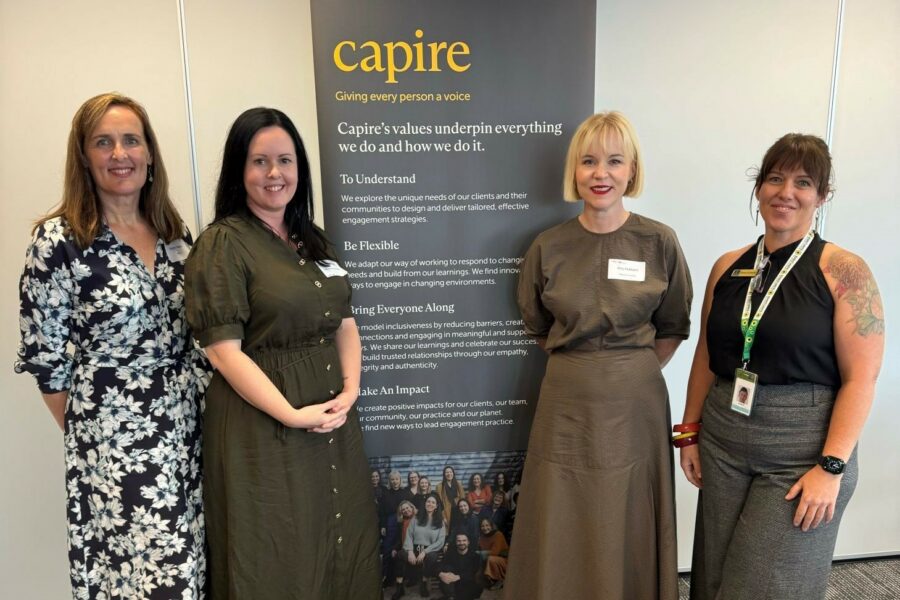Sophie Walker, Tamara Weaver, Amy Hubbard and Kerry O'Connor attend the IAP2A / Capire networking event in Brisbane. They are dressed in business clothes and standing in front of a Capire banner, smiling at the camera.