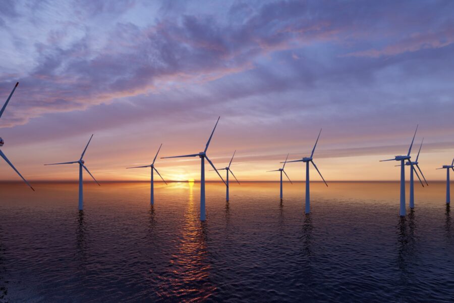 An offshore wind farm at sunset. Cloudy blue-grey sky above