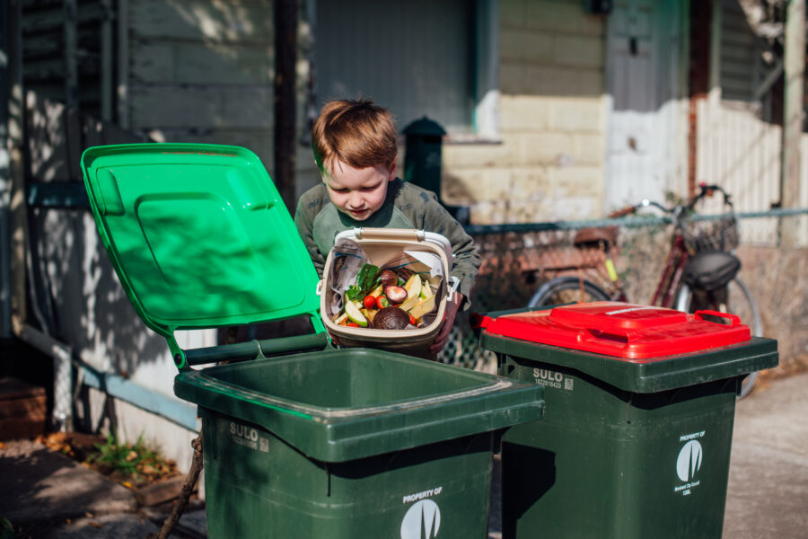 A young boy emptying green waste into a bin