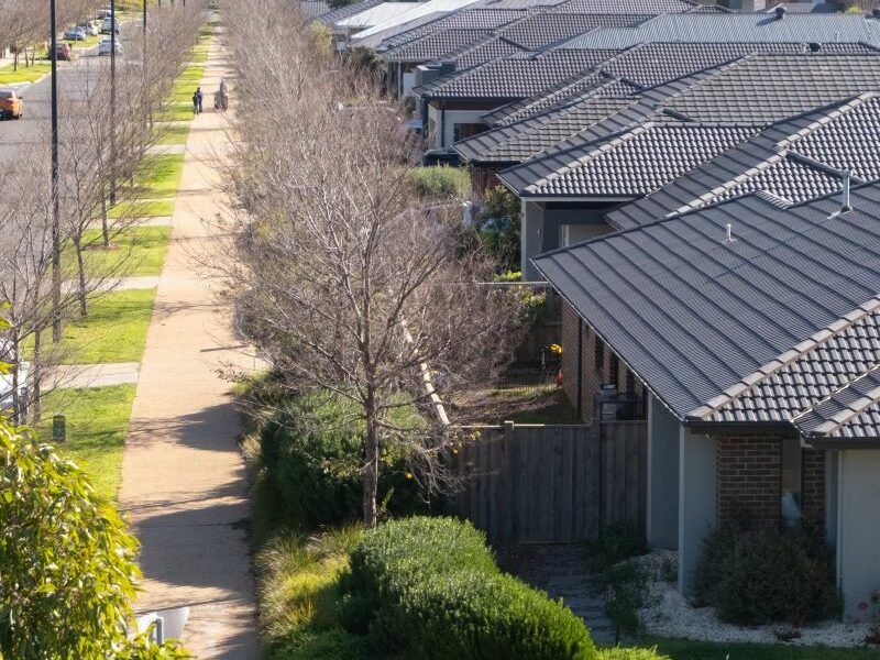 A strip of modern houses in a new estate in a Melbourne suburb. Footpath, nature strips and road also visible