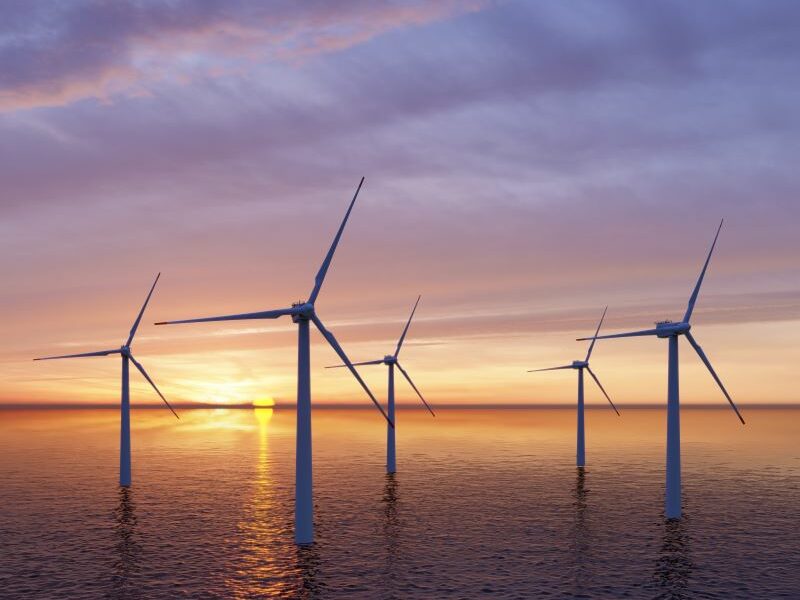 An offshore wind farm at sunset. Cloudy blue-grey sky above